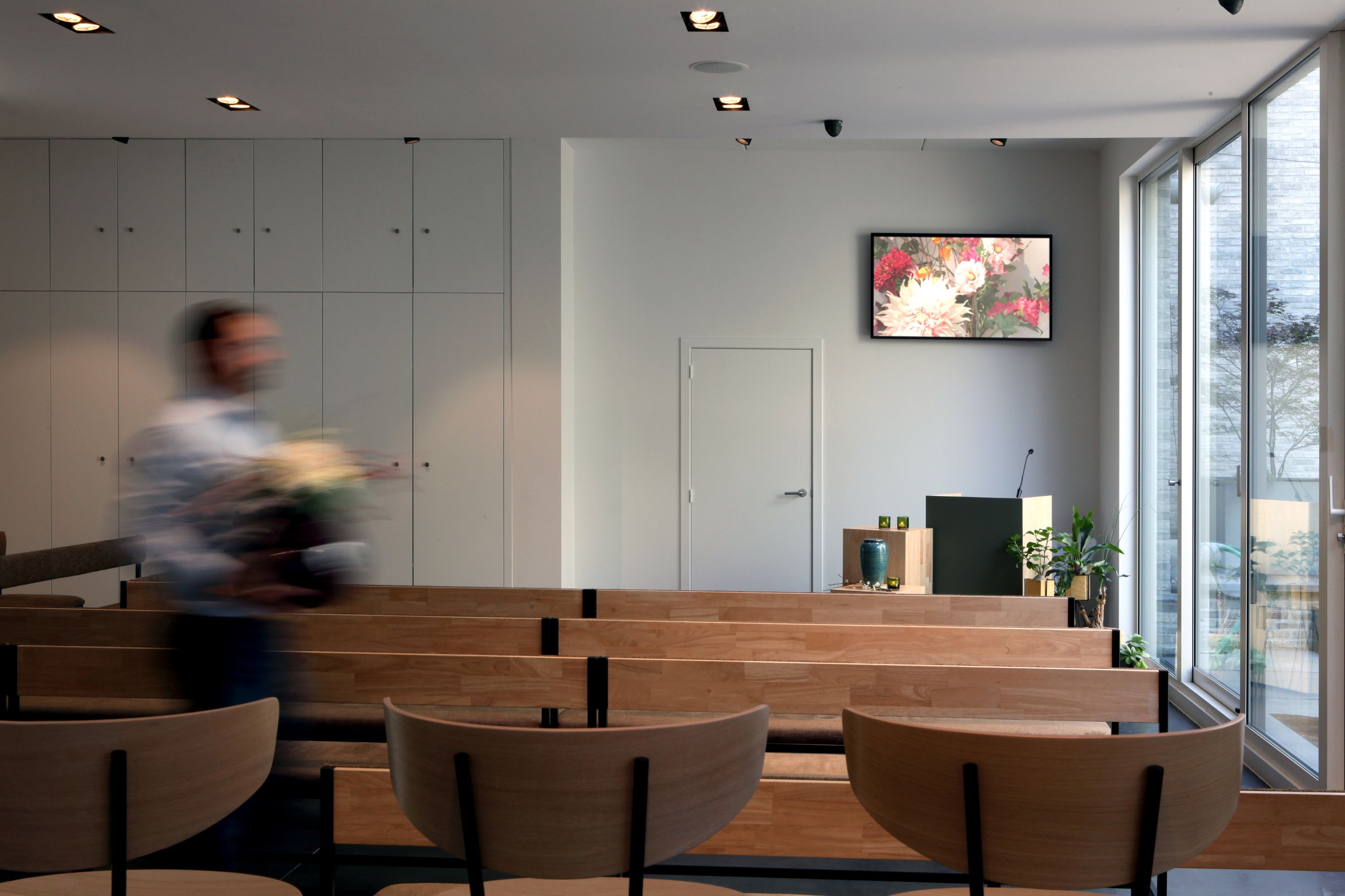Van Kuyk Uitvaartcentrum Antwerpen — aula met houten zitbanken en schermen